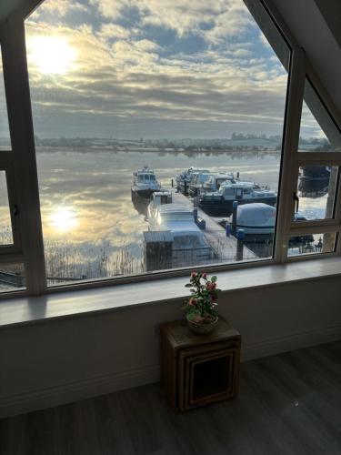 a window with a view of a marina with boats at Lough Key Luxury Riverfront Apartment in Cootehall