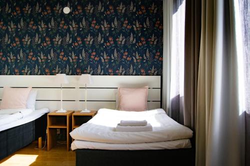 a room with two beds and a wall with a wallpaper at Hotel Sea Front in Tammisaari