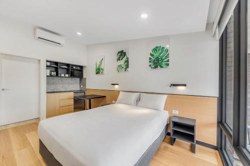 a bedroom with a large white bed and a kitchen at Parkview Motor Inn in Parkes