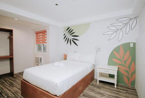 a bedroom with a white bed and a plant wall at Lea Robert Hotel Angeles Pampanga by RedDoorz in Angeles