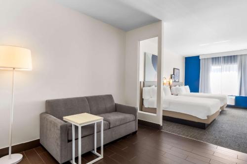 a living room with a couch and a bed and a mirror at Spark by Hilton Pearland in Pearland