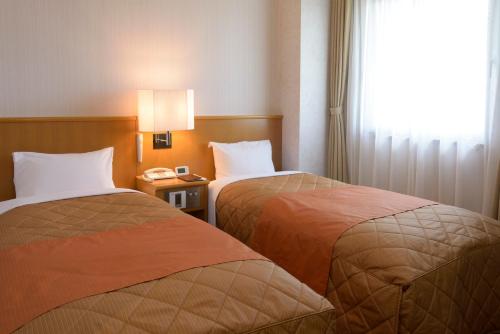 むつ市にあるホテルフォルクローロ大湊のベッド2台、電話が備わるホテルルームです。