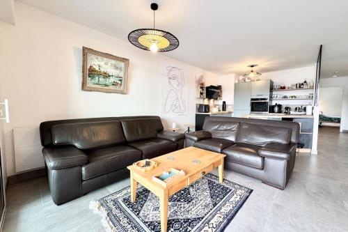 - un salon avec un canapé en cuir et une table basse dans l'établissement T3 de standing - Vue océan 180, à Guidel