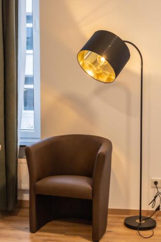 a black lamp with a brown chair and a lampshade at HLN APARTMENTS Am Bahnhof in Saarbrücken