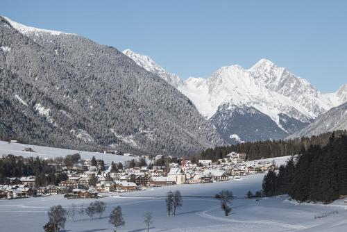 a small town in the snow with mountains in the background at Hotel Brötz in Rasùn di Sotto