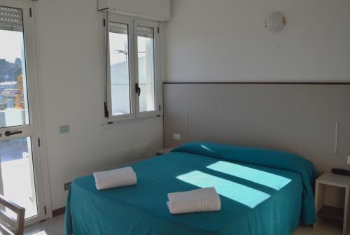 a bedroom with a blue bed with two towels on it at Hotel Caesar in Pesaro