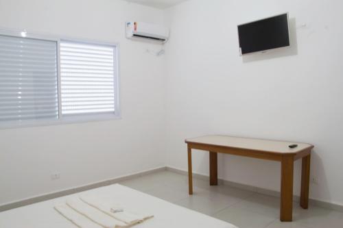 Habitación con mesa y TV en la pared. en Consulado Praia Hotel, en Guarujá