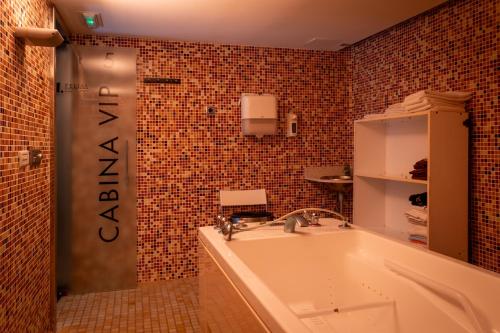 a bathroom with a tub and a tiled wall at Hotel Felisa SPA in Queveda