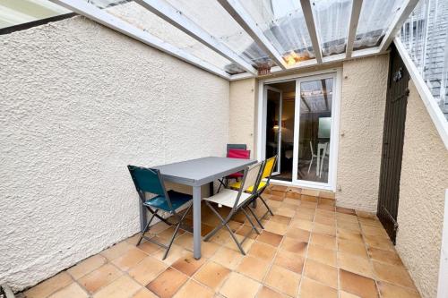 une table et des chaises sur une terrasse avec un toit en verre dans l'établissement Maisonnette neuve - 700m des plages - Piscine, à Guidel