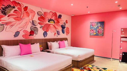 two beds in a room with pink walls at Yellow Bee Resort Cililitan in Jakarta