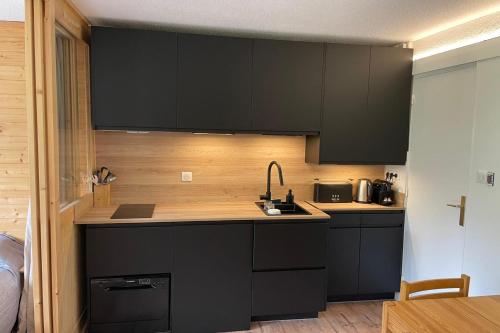 - une cuisine avec des placards noirs et un évier dans l'établissement Pretty T2 with balcony and view to the slopes, à Saint-Chaffrey