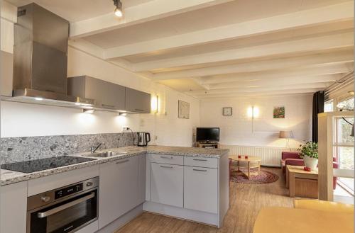 eine Küche mit weißen Geräten und ein Wohnzimmer in der Unterkunft Bungalowpark Simpelveld - Schakel 24 in Simpelveld