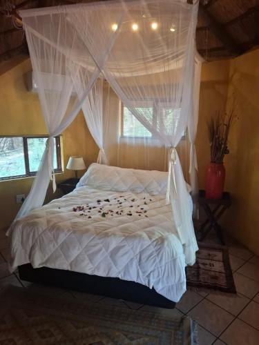 a bedroom with a white bed with a canopy at Jabula Kruger Safari Lodge in Marloth Park