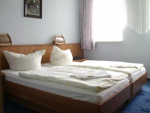 a bed with white sheets and pillows in a room at Hotel-Restaurant Marcus in Malchin