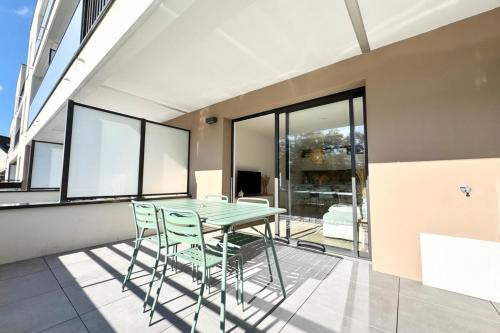 Una mesa y sillas en una habitación con ventanas. en Lovely ! T3 de standing - Proche bourg et plages, en Ploemeur