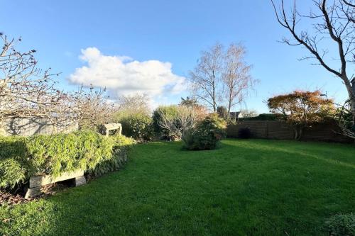 a yard with a green lawn with bushes and trees at Spacieuse longère archi cosy - Jardin in Quimperlé
