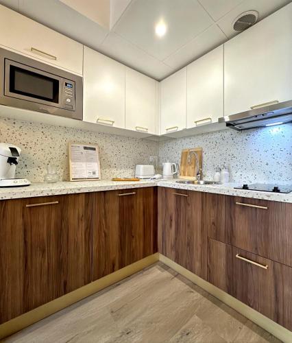 een keuken met houten kasten en een magnetron bij L'Écrin de Jaude - Duplex by PRIM0 C0NCIERGERIE in Clermont-Ferrand