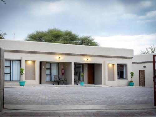 a white building with two chairs in front of it at Mango Self-catering Apartments in Ghanzi