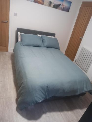 a large bed with blue sheets and pillows in a bedroom at Elmer belle beach Bognor regis accommodation in Yapton