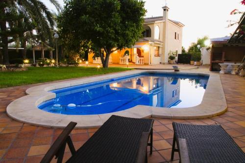 a pool in a yard with two chairs and a house at Villa Iluminada con chimenea, barbacoa y piscina cerca Playa in Elche