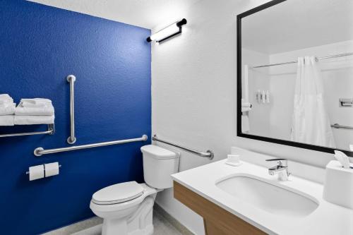 a bathroom with a white toilet and a blue wall at Spark by Hilton Daleville Roanoke North in Daleville
