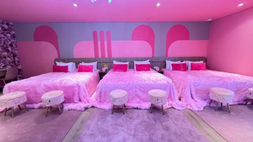 two beds in a pink room with pink furniture at Yellow Bee Resort Cililitan in Jakarta