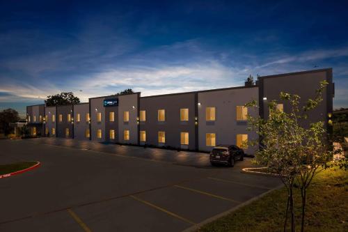 a building with a car parked in a parking lot at Clarion Pointe - Fort Worth Arlington West in Fort Worth