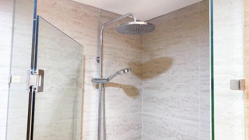 a shower with a glass door in a bathroom at Modern Look and Warm 1BR at Gold Coast Apartment By Travelio in Jakarta