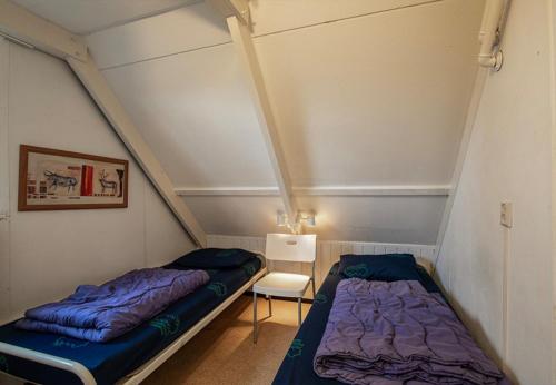ein Schlafzimmer mit zwei Betten und einem Stuhl in der Unterkunft Bungalowpark Simpelveld - Alpha 105 in Simpelveld