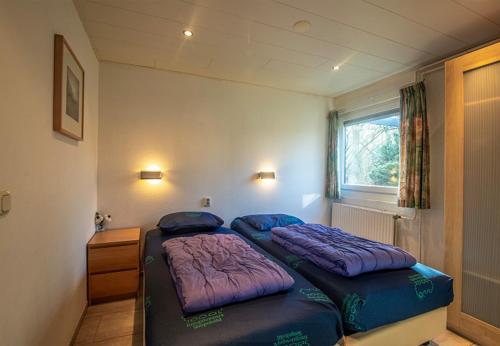 a bedroom with two beds with purple pillows at Bungalowpark Simpelveld - Schakel 5 in Simpelveld