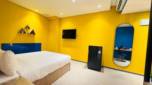 a bedroom with a bed and a yellow wall at Yellow Bee Resort Cililitan in Jakarta