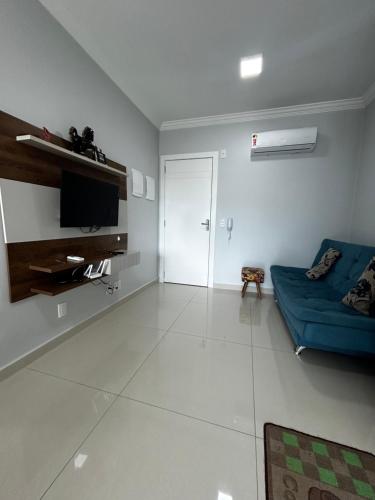 a living room with a blue couch and a television at APARTAMENTO BRISA do SOL 202 in Piratuba