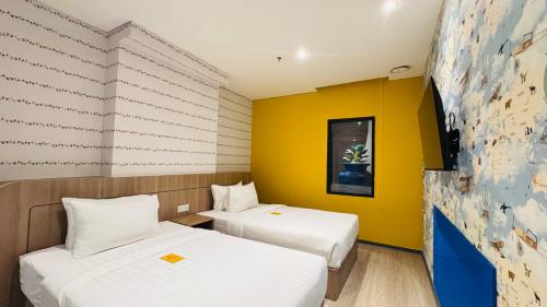 two beds in a room with a yellow wall at Yellow Bee Resort Cililitan in Jakarta