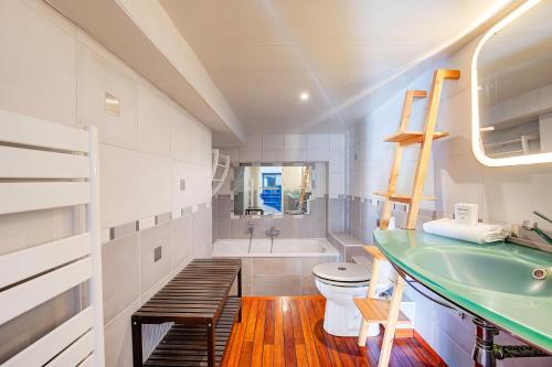 une salle de bain avec un lavabo, des toilettes et une baignoire dans l'établissement Loft atypique avec bowling pour 12 voyageurs, cabinet des curiosités, à La Riche