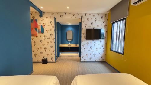 a room with two beds and a tv on a wall at Yellow Bee Resort Cililitan in Jakarta