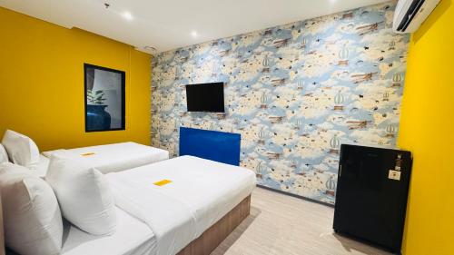 two beds in a room with yellow walls and a tv at Yellow Bee Resort Cililitan in Jakarta