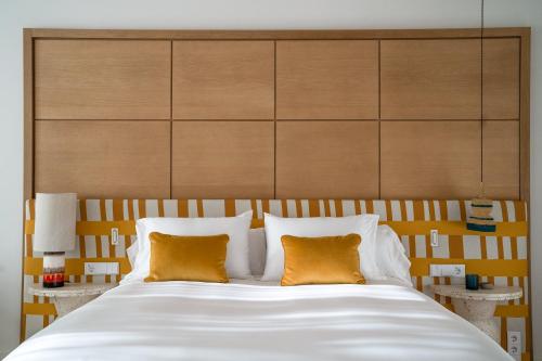 a bedroom with a large white bed with two orange pillows at Kimpton Los Monteros Marbella by IHG in Marbella