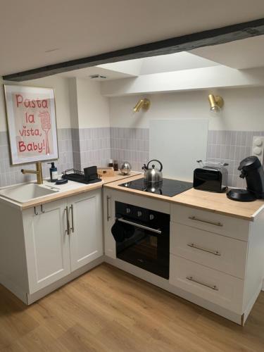 La cuisine est équipée de placards blancs et d'un four avec plaques de cuisson noires. dans l'établissement Appartement coeur de ville - 4 couchages, à Nantes