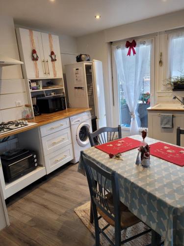 una cocina con mesa y una cocina con estufa en Appartement Au Cigogneau Wifi-Netflix-Balcon-Parking, en Munster