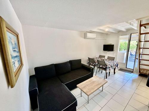 un salon avec un canapé noir et une table dans l'établissement PN200-024 Maison 3 pièces - 4 couchages PORT LA NOUVELLE, à Port-la-Nouvelle