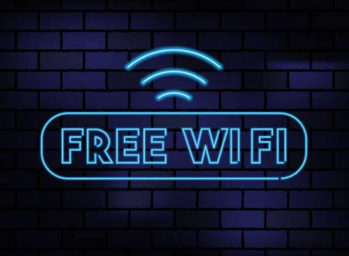 a neon sign with a free wifi sign on a brick wall at Britannia Inn Glasgow in Glasgow