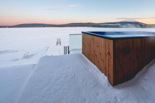 a hot tub in the snow next to a snow covered field at Stay North - Joiku - Midnight Sun in Äkäslompolo