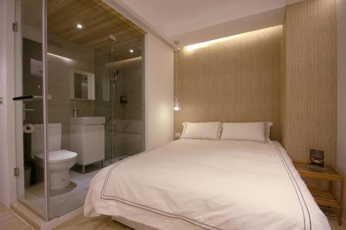 a bedroom with a bed and a shower and a toilet at Mini West Hotel in Taichung