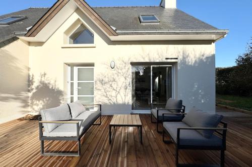 a patio with two chairs and a couch on a wooden deck at Maison de vacances tout confort - 300m des plages in Larmor-Plage