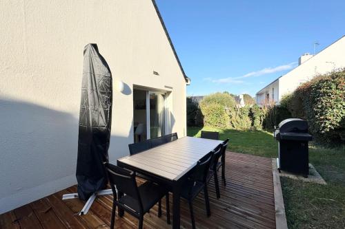 a wooden deck with a table and chairs on it at Maison de vacances tout confort - 300m des plages in Larmor-Plage
