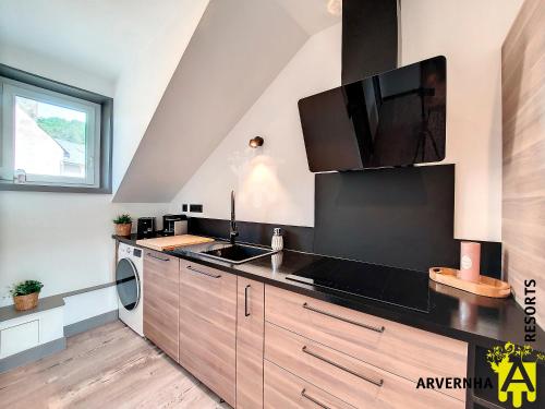 une cuisine avec un évier et un micro-ondes dans l'établissement La Petite Hirondelle, à Murol