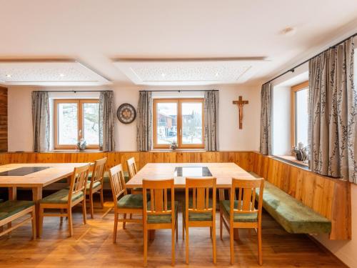 a dining room with wooden tables and chairs and windows at Farmhouse in Bramberg with Natural Pond in Dorf