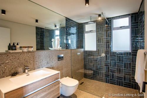 a bathroom with a sink and a toilet and a shower at High Tide at Umdloti Resort in Umdloti