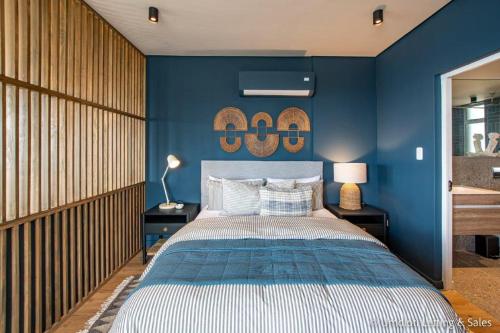 a bedroom with a blue wall with a bed at High Tide at Umdloti Resort in Umdloti