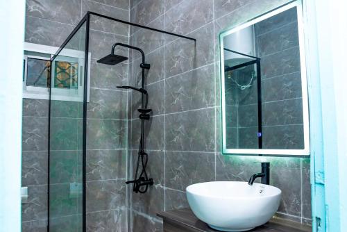 a bathroom with a sink and a shower with a mirror at Maison meublée avec parking et jardin in New Bell